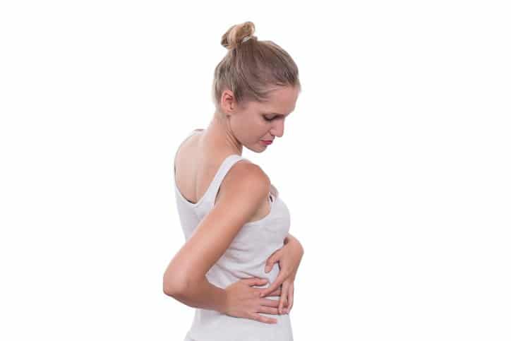 Young female touching right side of body in pain. Kidney pain. Isolated on white background