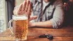 Do not drink and drive! Cropped image of man showing stop gesture and refusing to drink beer. Car keys lying near