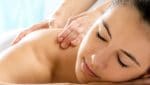 Close up portrait of young woman relaxing in spa.Therapist doing back massage on girl in background.