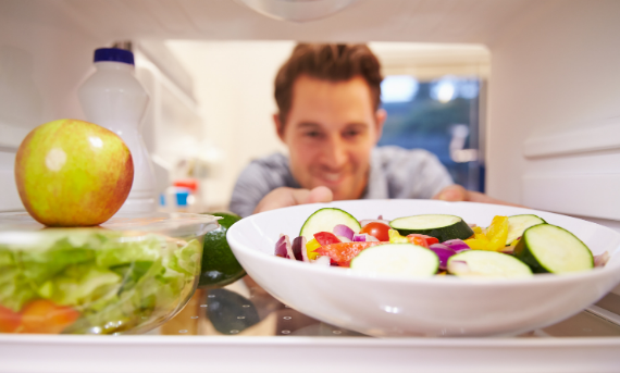 Man reaching for salad in fridge